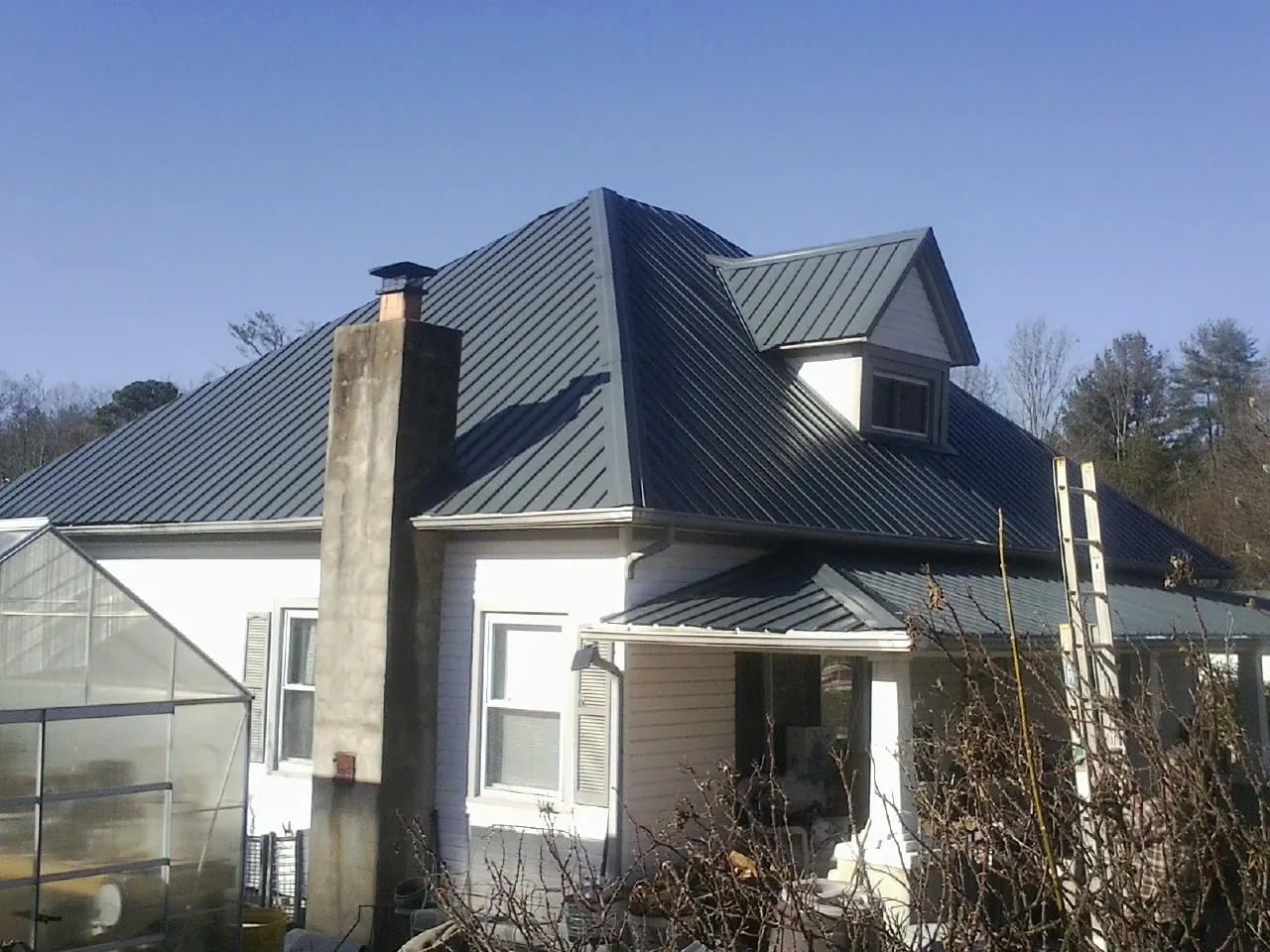 Dark blue standing seam metal roof on a white farmhouse with dormer — Slate & Tile Roof Repair by Roofing Brothers in Homedale