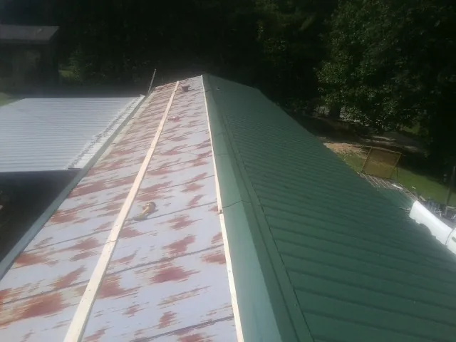 Old rusted panels beside newly installed green metal roofing — Wind Damage Roof Repair by Roofing Brothers in Homedale