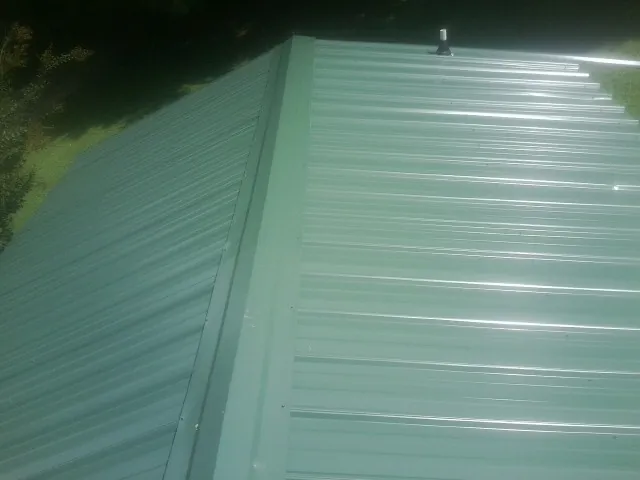 New green metal panels meeting at the ridge of a roof — Flat Roof Repair work by our crew in Homedale