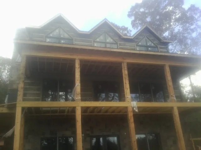 Dormers and porch framing on a large log home under construction — Roof Coating work by our crew in Homedale