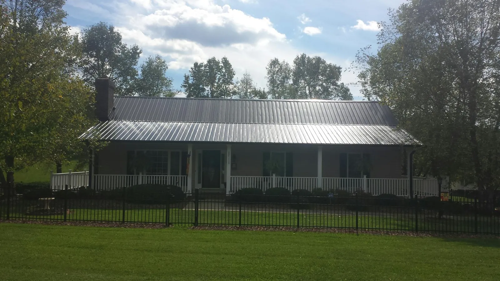 Gray metal roof on a brick ranch with a full width front porch — Gutter Guard Installation work by our crew in Homedale