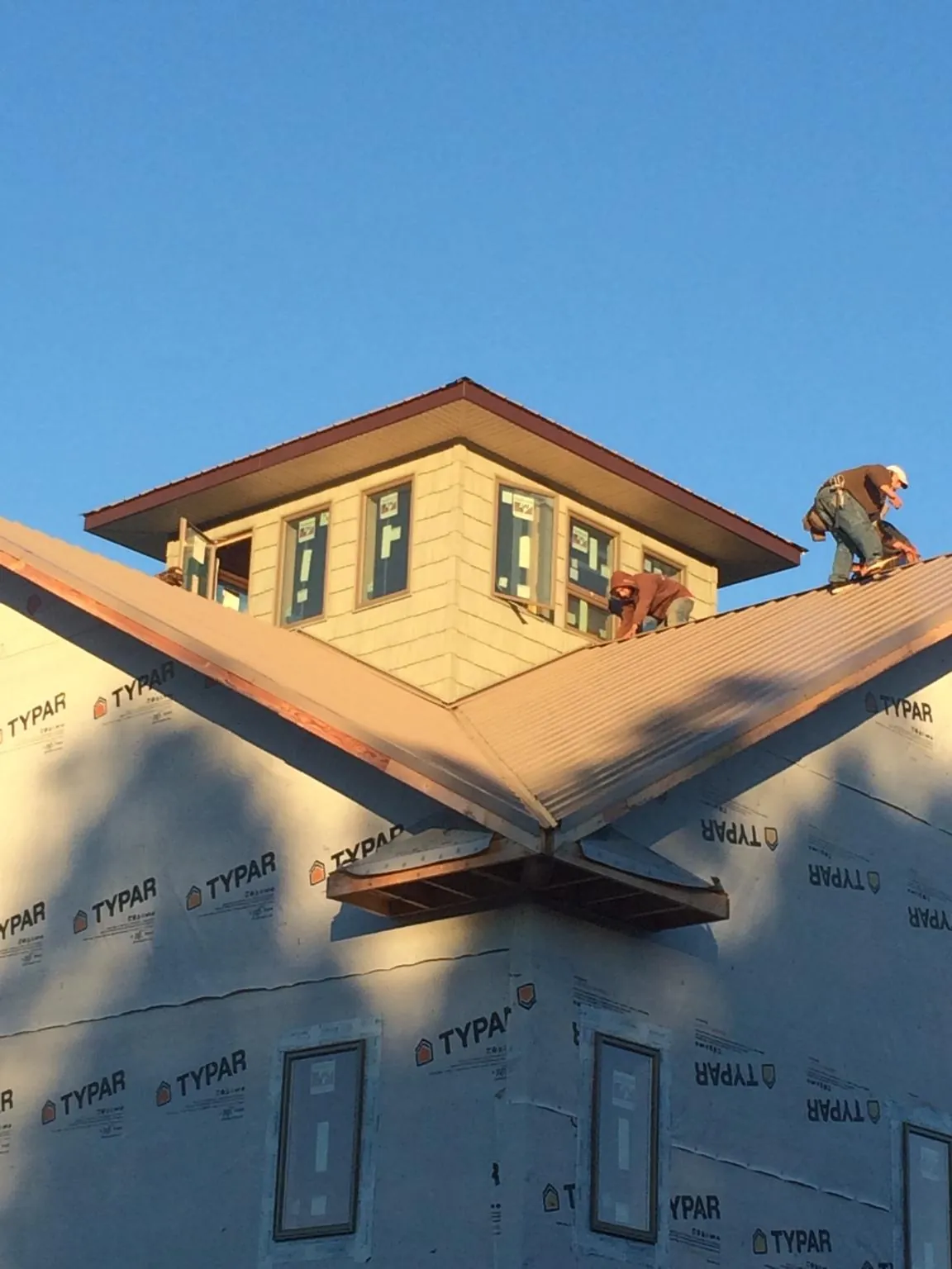 Roofers working around a rooftop cupola on a new metal roof at sunset — Roof Waterproofing in Homedale by Roofing Brothers
